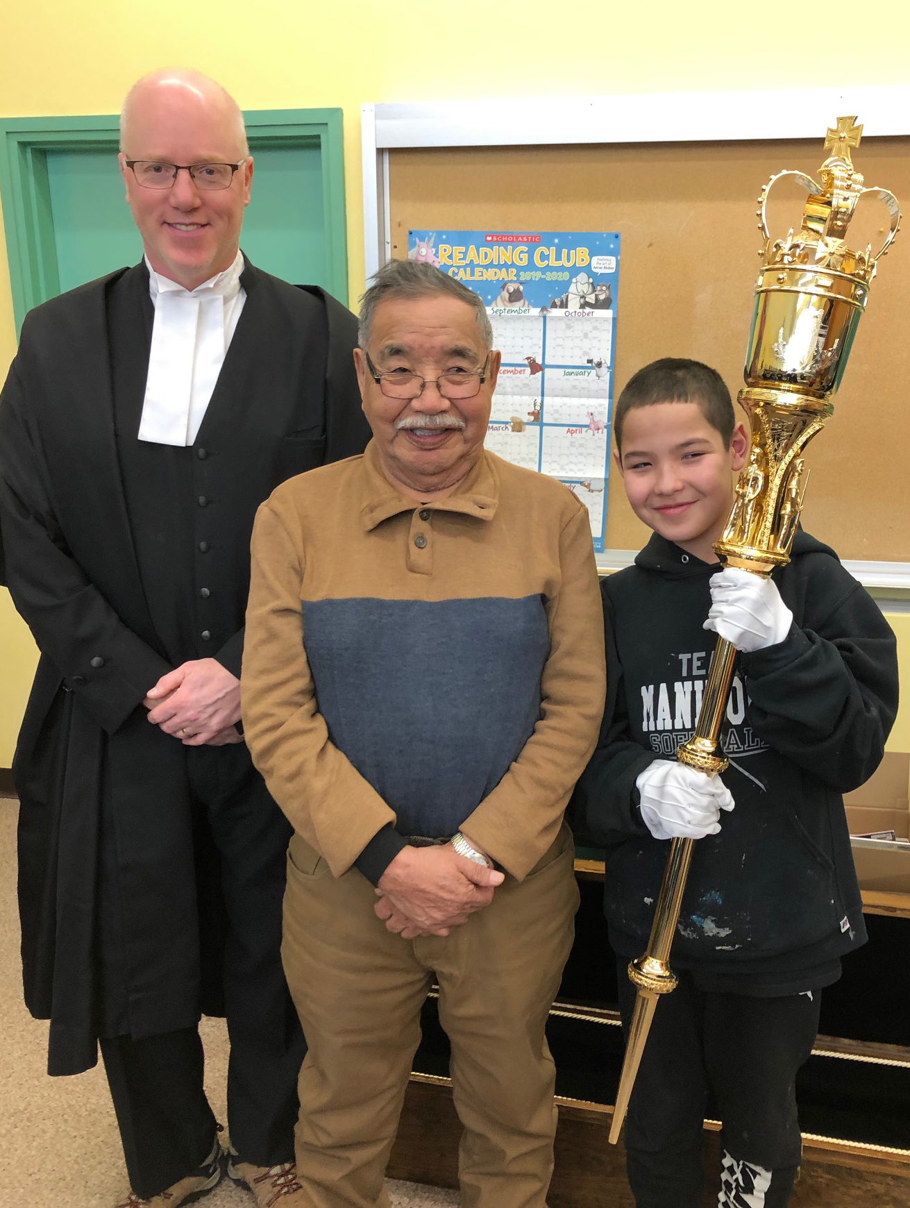 Sam Johnston, his grandson Seth Netro, and the Hon. Nils Clarke are pictured with Seth holding the Mace
